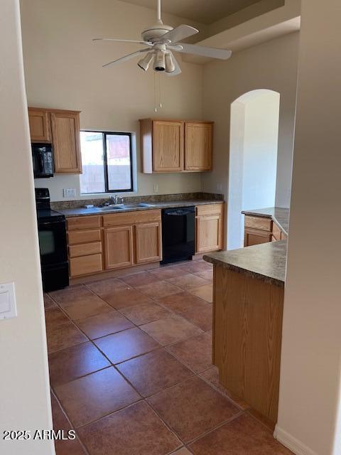 kitchen with ceiling fan, a sink, black appliances, a towering ceiling, and tile patterned floors