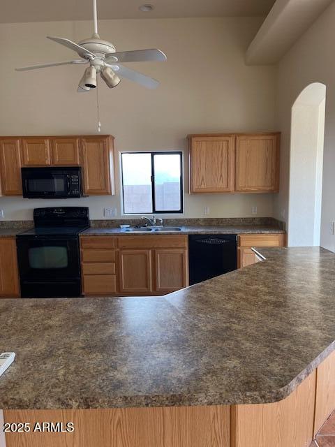 kitchen with a sink, dark countertops, black appliances, and a towering ceiling