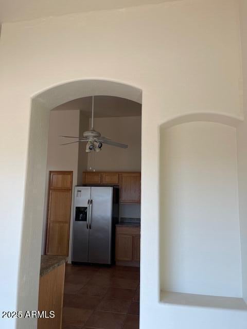 kitchen featuring dark countertops, dark tile patterned flooring, a ceiling fan, and stainless steel fridge with ice dispenser