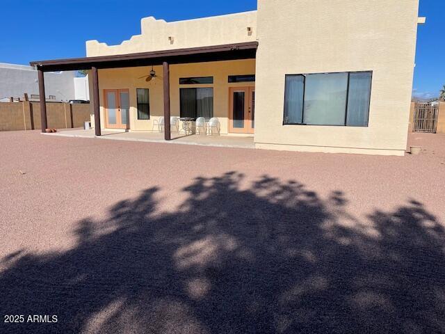 back of house with stucco siding, fence, french doors, ceiling fan, and a patio area