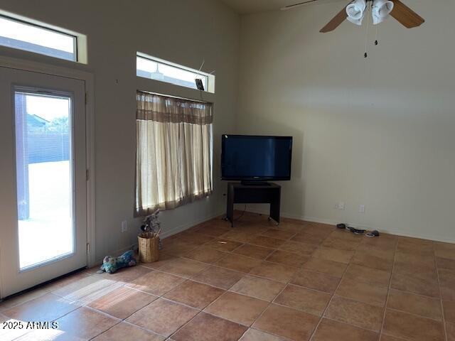 unfurnished living room featuring a wealth of natural light, tile patterned floors, and a ceiling fan