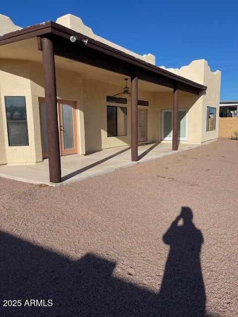 rear view of property featuring a ceiling fan, a patio area, and stucco siding