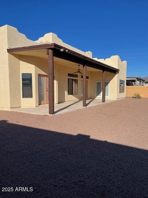 rear view of property with stucco siding, ceiling fan, and a patio area