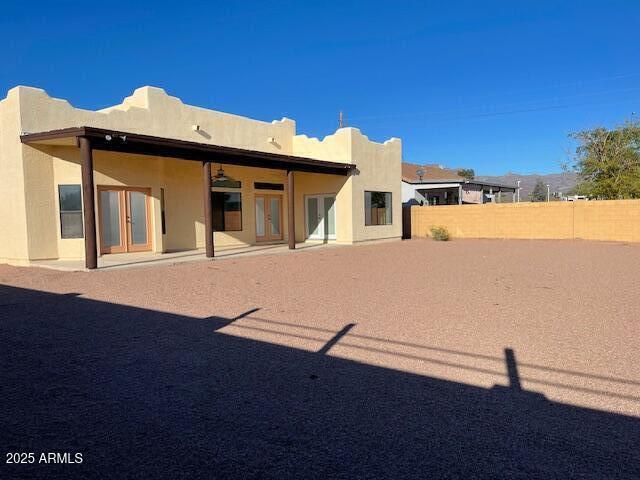 back of property with stucco siding, a fenced backyard, and french doors