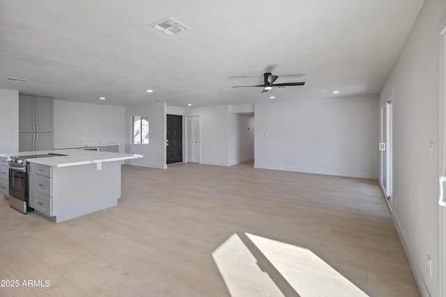 kitchen featuring ceiling fan, gray cabinetry, light hardwood / wood-style floors, a kitchen island, and stainless steel electric stove