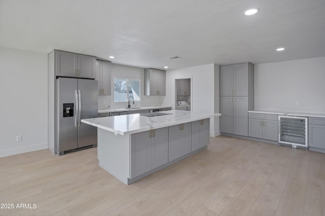 kitchen with gray cabinetry, stainless steel fridge, beverage cooler, and a kitchen island