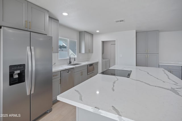 kitchen featuring light stone counters, sink, gray cabinets, and appliances with stainless steel finishes