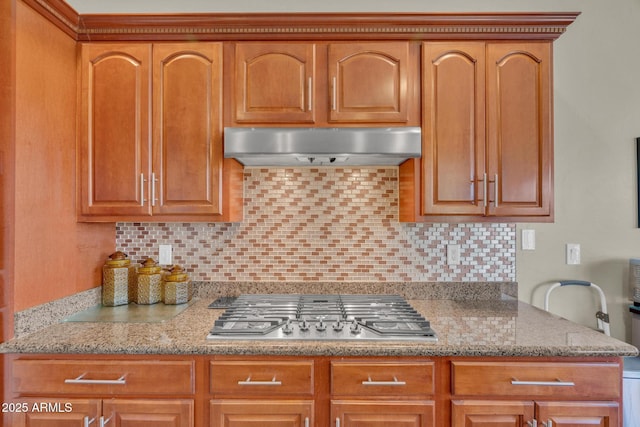 kitchen featuring under cabinet range hood, light stone counters, backsplash, and stainless steel gas cooktop