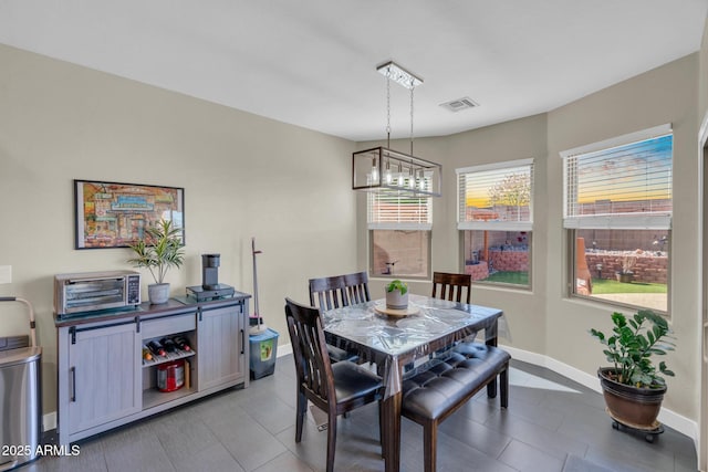 dining area featuring a toaster, visible vents, baseboards, and a notable chandelier
