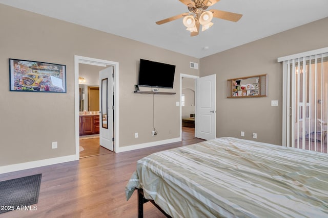 bedroom featuring baseboards, a ceiling fan, visible vents, and wood finished floors