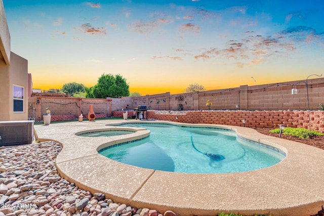 pool at dusk featuring central air condition unit, an in ground hot tub, a fenced in pool, and a fenced backyard