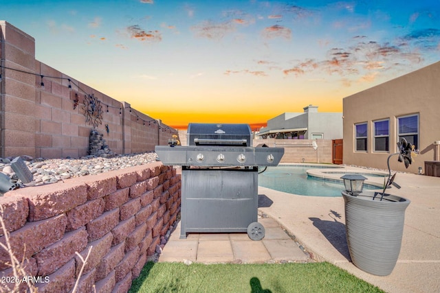 pool at dusk featuring a fenced backyard, grilling area, a patio area, and a fenced in pool