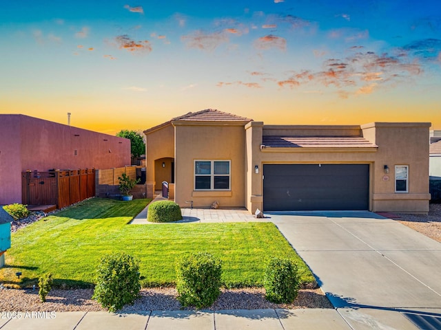 view of front facade featuring fence, an attached garage, stucco siding, concrete driveway, and a front lawn