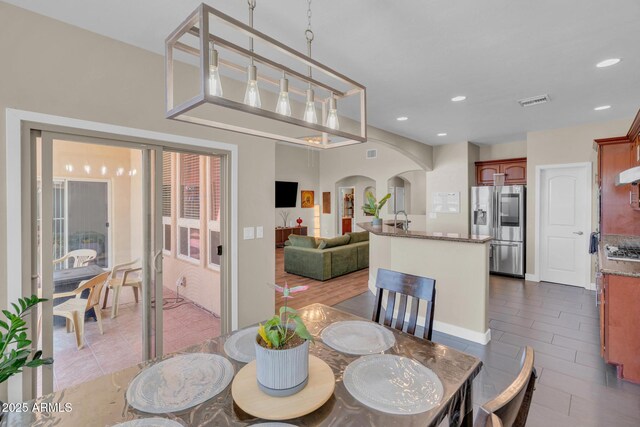 dining area featuring dark tile patterned floors, visible vents, arched walkways, and recessed lighting