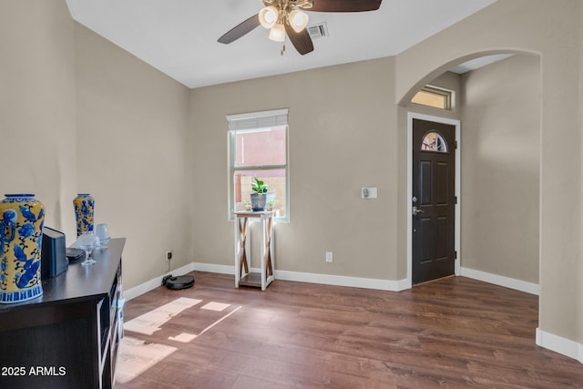 foyer entrance with arched walkways, baseboards, a ceiling fan, and wood finished floors