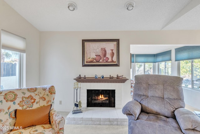 living room with a brick fireplace, a textured ceiling, and carpet