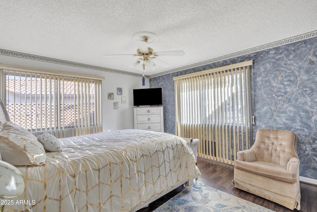 bedroom featuring ceiling fan, wood-type flooring, ornamental molding, and a textured ceiling