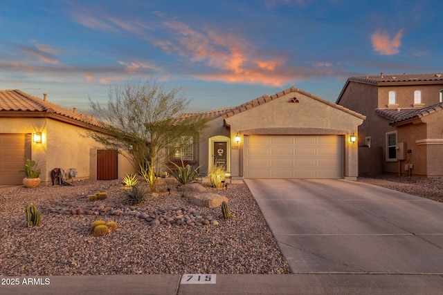 mediterranean / spanish house featuring concrete driveway, a tile roof, an attached garage, and stucco siding