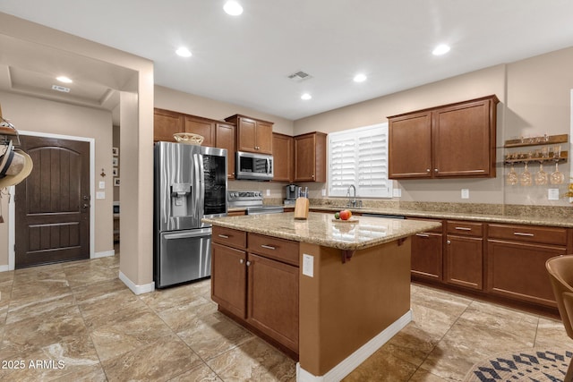 kitchen featuring visible vents, a kitchen island, appliances with stainless steel finishes, light stone counters, and recessed lighting