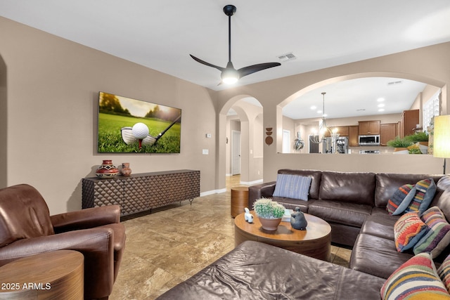 living area with baseboards, visible vents, arched walkways, and a ceiling fan