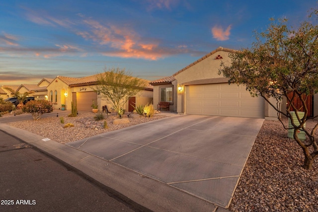 mediterranean / spanish-style home with a garage, driveway, a tiled roof, and stucco siding