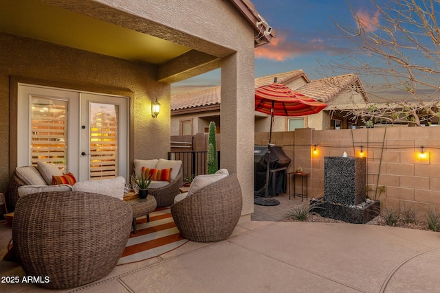 patio terrace at dusk featuring outdoor lounge area, fence, and a grill