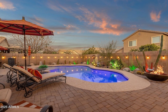 pool at dusk with a fenced in pool, a patio area, and a fenced backyard