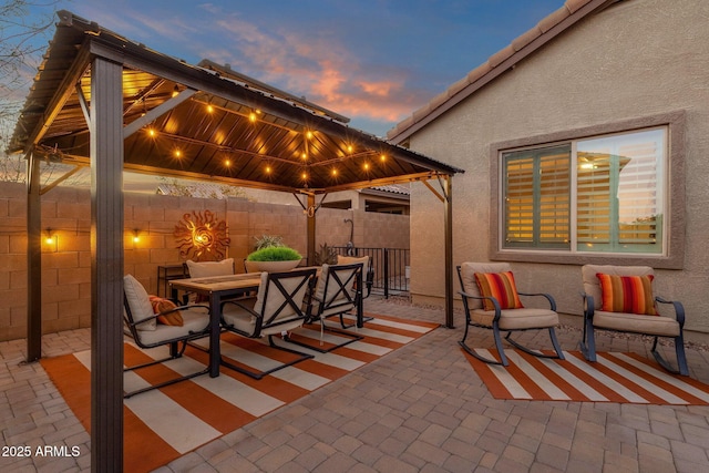 view of patio / terrace featuring outdoor dining area, fence, and a gazebo