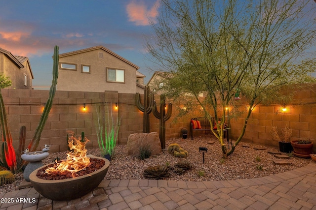 yard at dusk featuring a patio area, a fenced backyard, and a fire pit