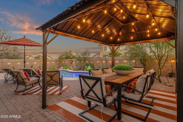 patio terrace at dusk with a fenced in pool, outdoor dining area, a fenced backyard, and a gazebo