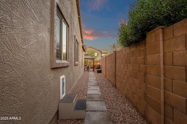 property exterior at dusk featuring fence and stucco siding