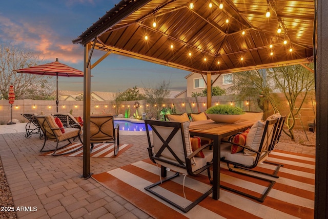 patio terrace at dusk featuring a gazebo, outdoor dining space, a fenced backyard, and a fenced in pool