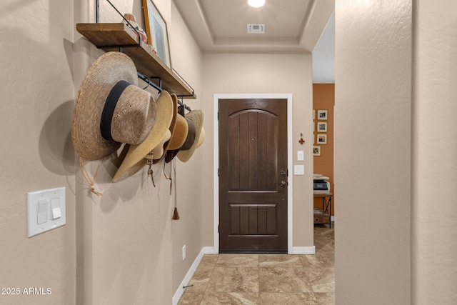 entryway with baseboards, visible vents, and a tray ceiling