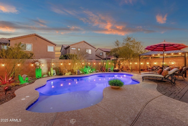 pool at dusk with a fenced in pool, a patio area, a fenced backyard, and an outdoor hangout area