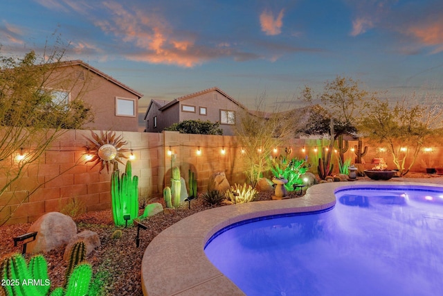 pool at dusk with a fenced backyard