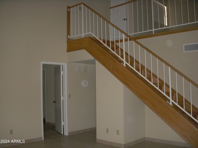 stairs featuring tile patterned flooring and a towering ceiling