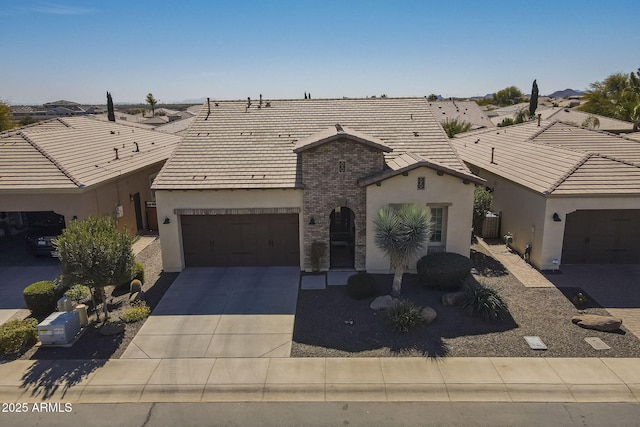 view of front facade featuring driveway, stucco siding, a tiled roof, and brick siding