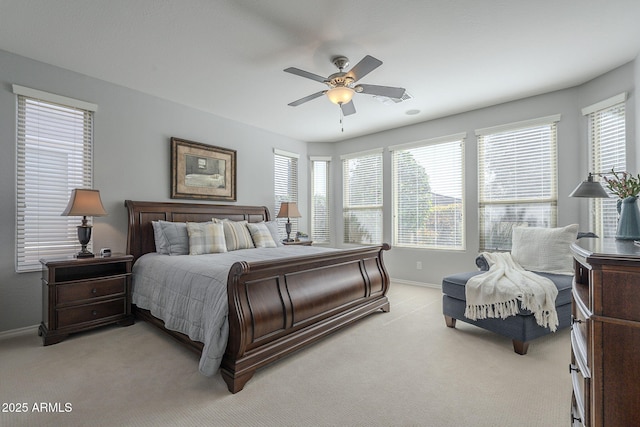 bedroom featuring light carpet, ceiling fan, multiple windows, and baseboards