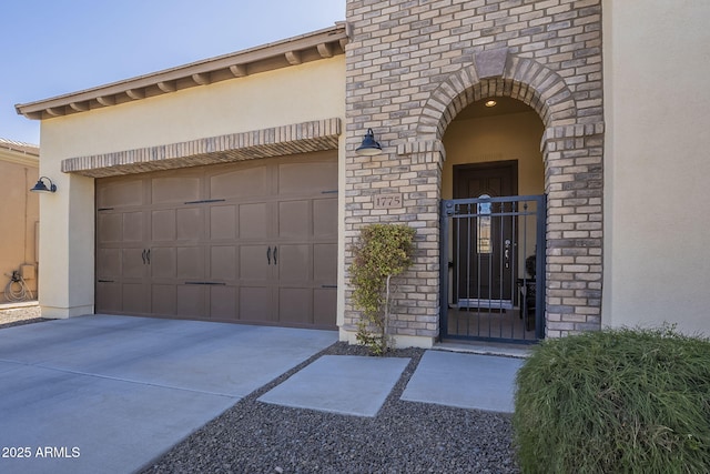 entrance to property featuring concrete driveway, an attached garage, and stucco siding