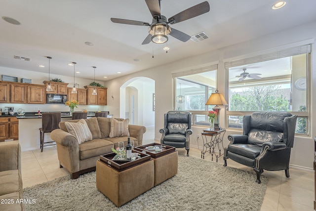 living room featuring arched walkways, light tile patterned flooring, plenty of natural light, and visible vents