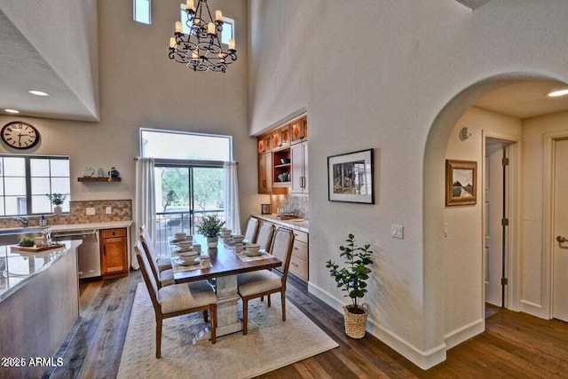 3935 E Rough Rider Rd Unit 1360, Phoenix, AZ 85050 - dining space featuring arched walkways, dark wood-style floors, plenty of natural light, baseboards, and a towering ceiling