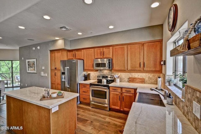 3935 E Rough Rider Rd Unit 1360, Phoenix, AZ 85050 - kitchen with appliances with stainless steel finishes, a sink, recessed lighting, brown cabinetry, and a kitchen island