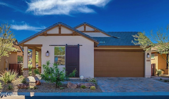 view of front of house with a garage, a tiled roof, decorative driveway, and stucco siding