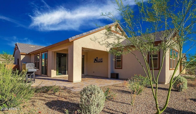 rear view of house featuring a patio area and stucco siding