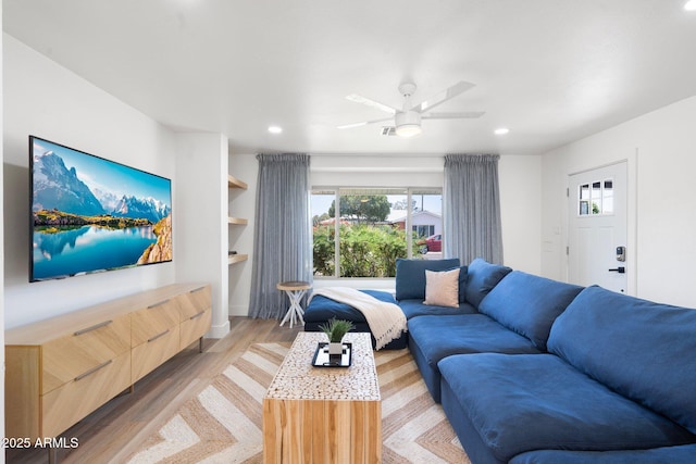 living room with ceiling fan, built in features, and light wood-type flooring