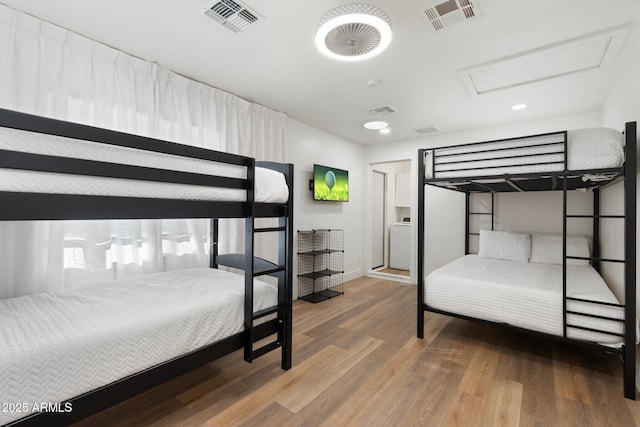 bedroom with washer / clothes dryer and wood-type flooring