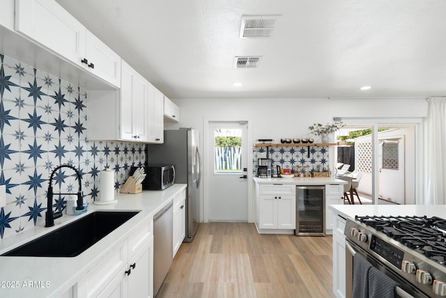 kitchen with tasteful backsplash, appliances with stainless steel finishes, beverage cooler, and sink