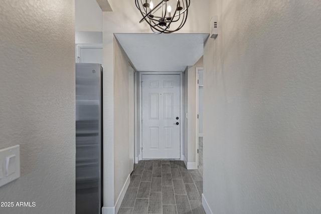 4165 E Huntington Dr, Phoenix, AZ 85040 - corridor featuring baseboards, a textured wall, a notable chandelier, and wood tiled floor