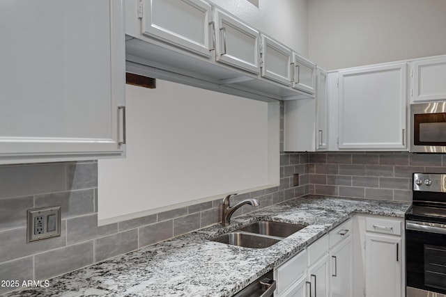 4165 E Huntington Dr, Phoenix, AZ 85040 - kitchen with white cabinetry, light stone counters, a sink, stainless steel appliances, and decorative backsplash