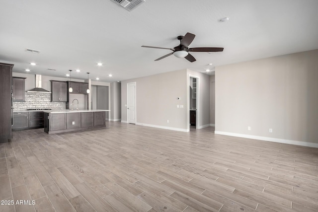 unfurnished living room with ceiling fan, sink, and light hardwood / wood-style floors